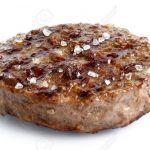 Single grilled hamburger patty with salt isolated on white.